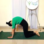 Woman practicing postnatal yoga with baby nearby